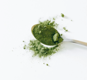 Matcha-Pulver in einer traditionellen Schale neben einem Bambusbesen und Teelöffel, mit Angabe der empfohlenen Dosierung von zwei Gramm pro Tag für optimale gesundheitliche Vorteile