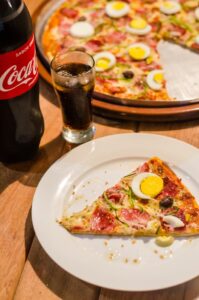 hochverarbeitete Lebensmittel wie Cola und Pizza nebeneinander auf dem Tisch