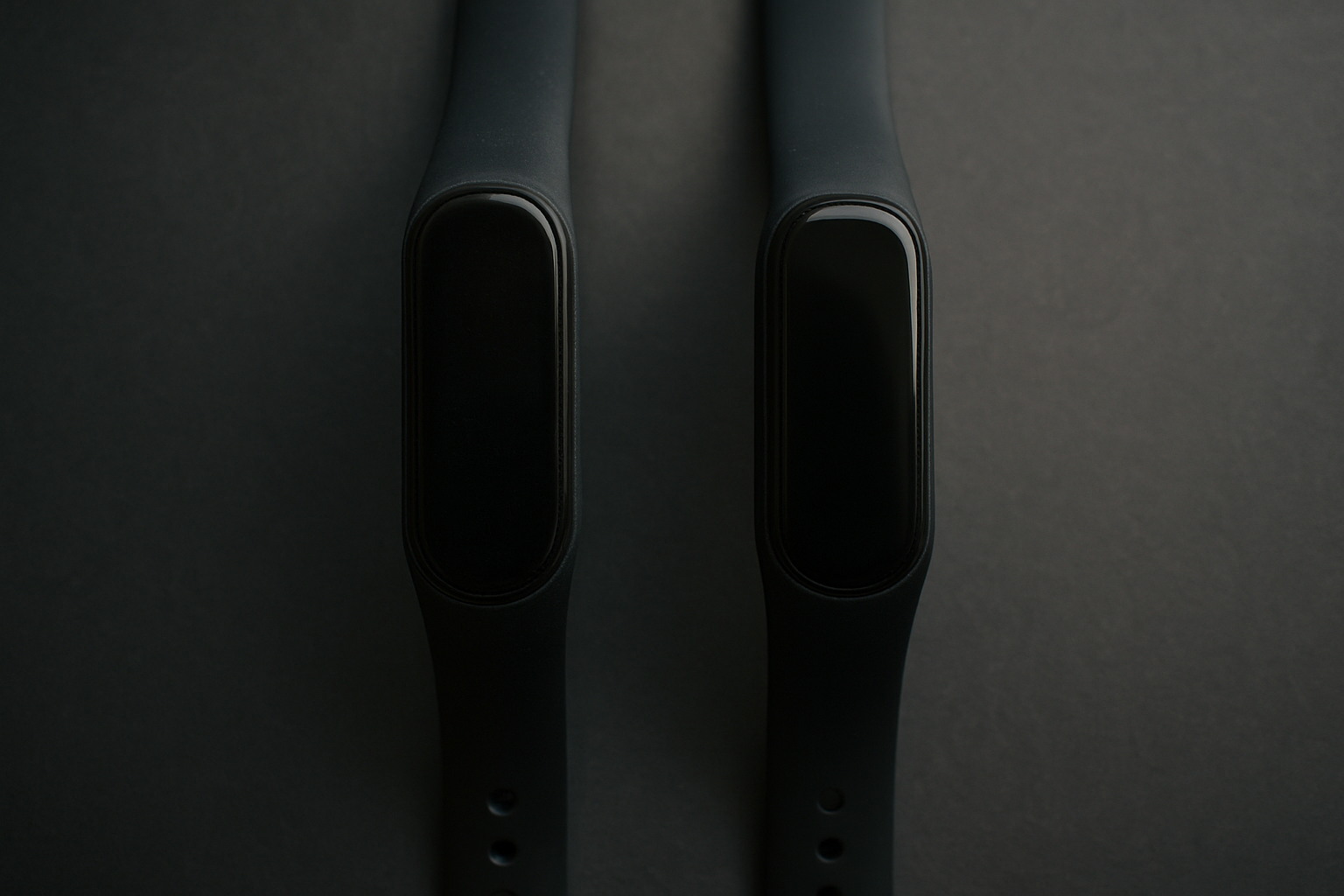 Vergleich zweier Generationen des Whoop-Fitnessbands nebeneinander auf dunkler Oberfläche